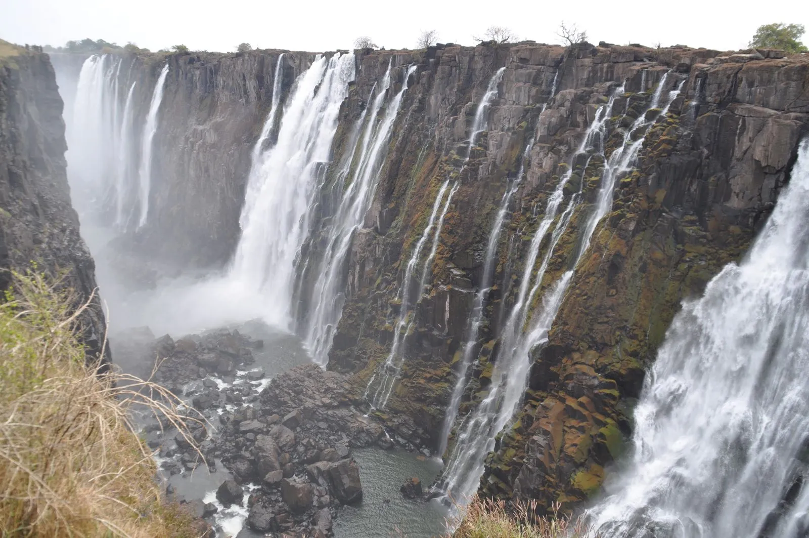 Dry-season view of thin streams falling down the bare basalt wall