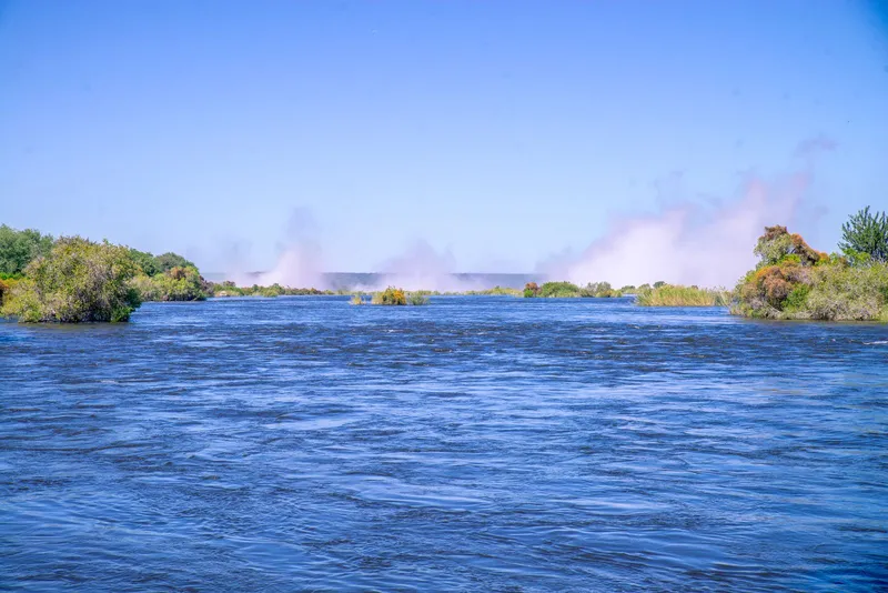 Wide Zambezi River with the spray of the falls rising in the distance