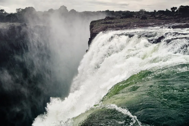 Green water curling over the lip of the falls into rising spray