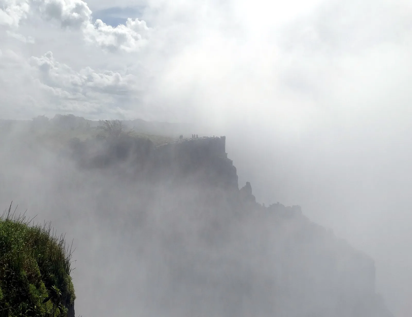 Cliff across the gorge half hidden by spray from the falls