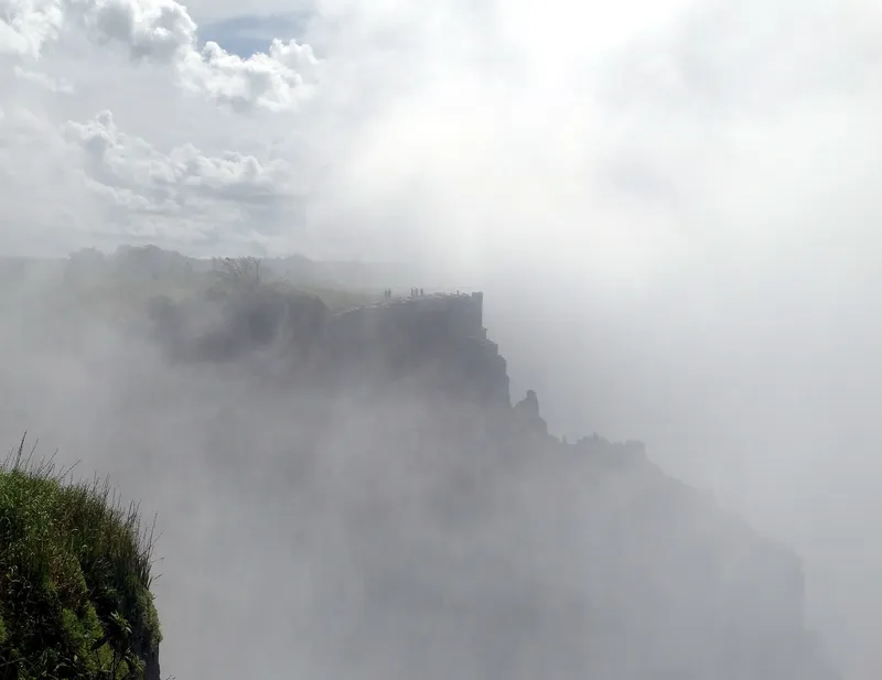 Cliff across the gorge half hidden by spray from the falls