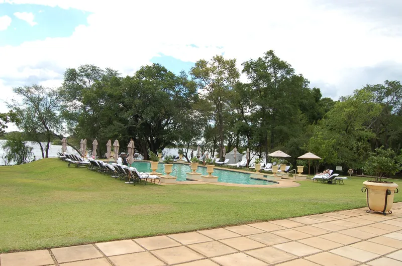 Pool and loungers at the Royal Livingstone Hotel, the Zambezi behind the trees