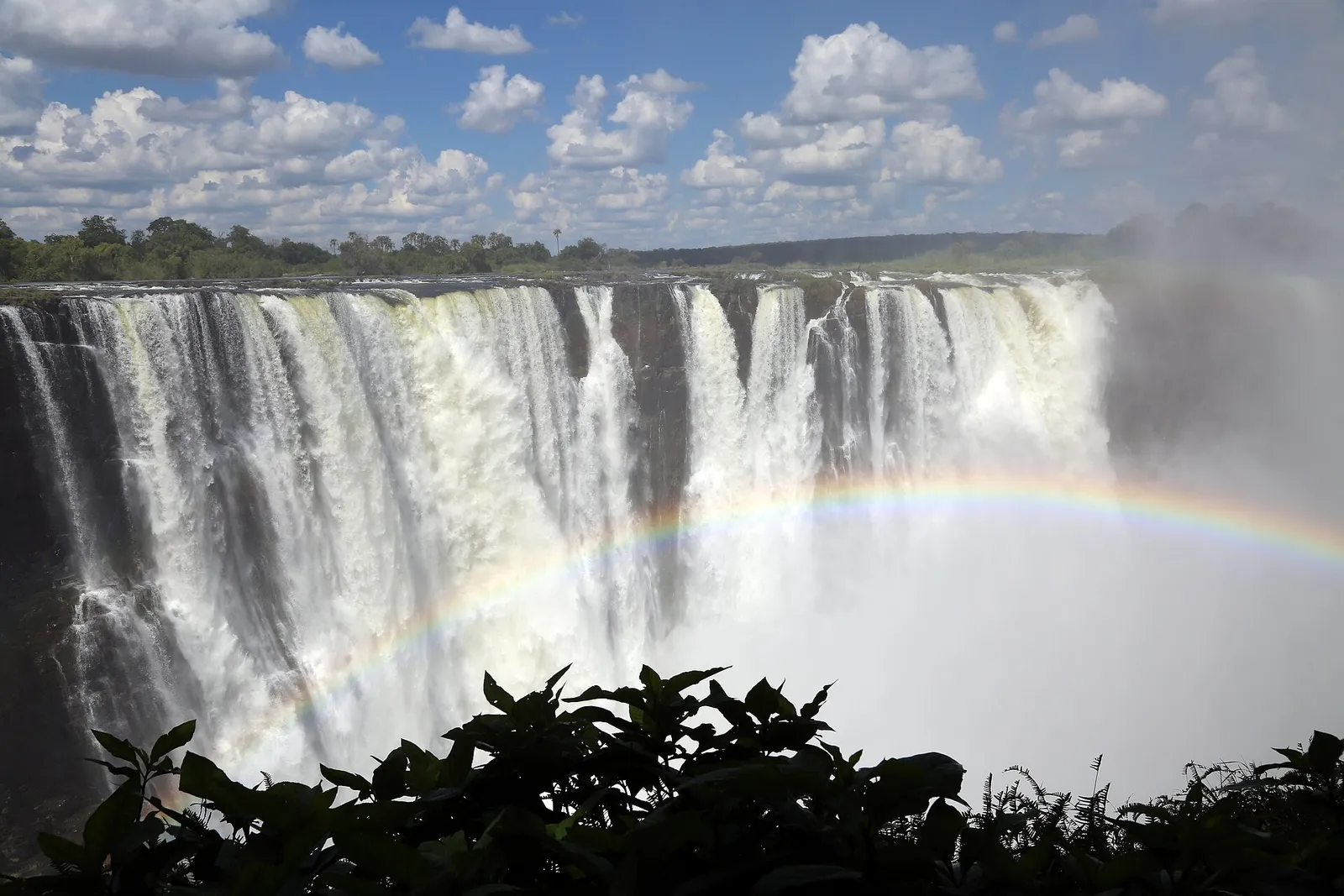 The falls with a rainbow in the spray, blue sky and clouds above