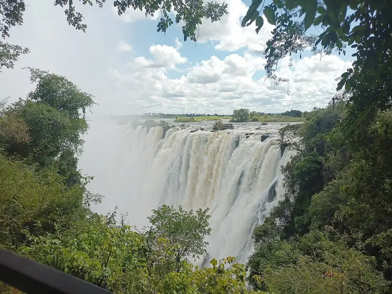 High-water falls seen through trees from the Zambian side