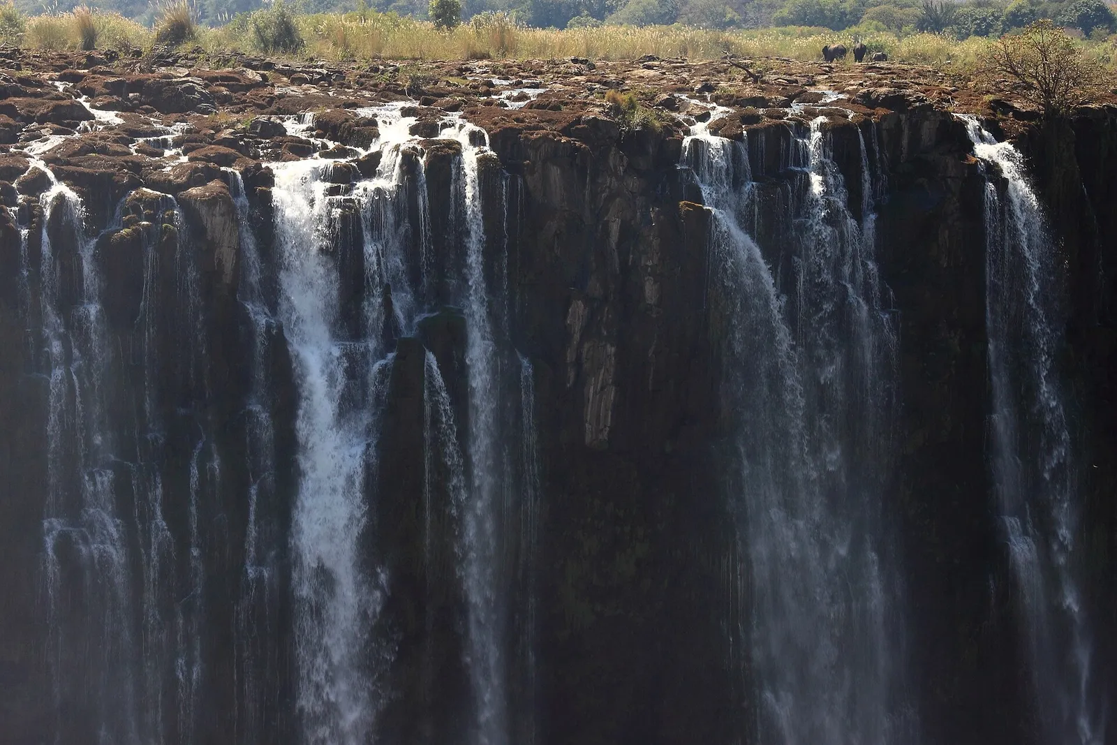 Low-water falls in the dry season, thin streams over dark basalt
