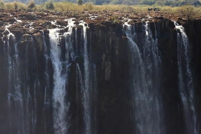 Low-water falls in the dry season, thin streams over dark basalt