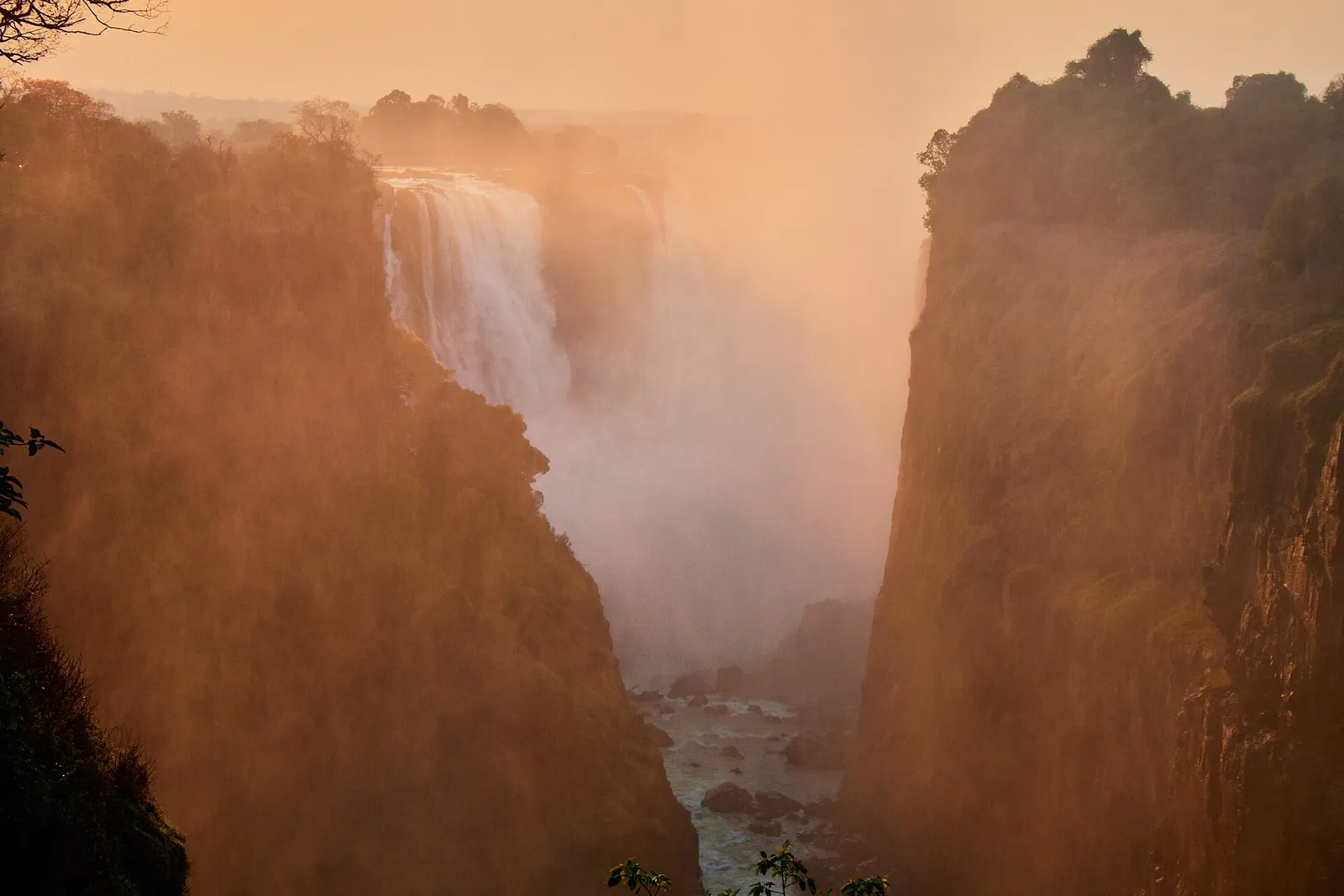 Spray glowing orange at sunset in the gorge below the falls