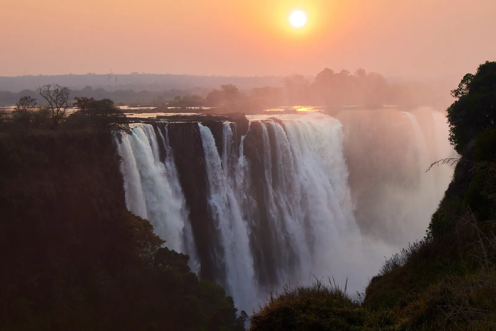 Victoria Falls on the Zambezi River, viewed from the Zimbabwe side at sunset.