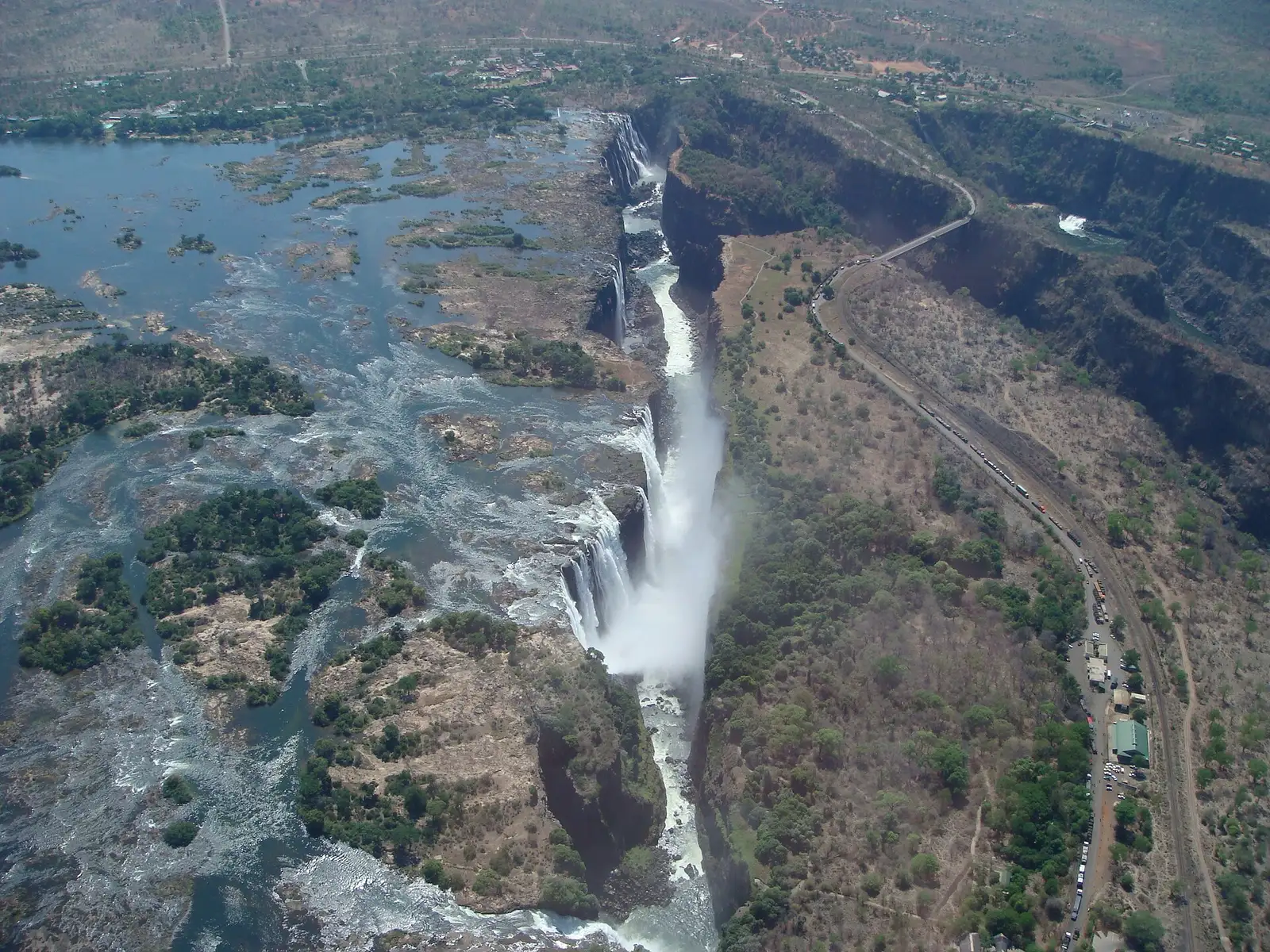 Aerial view of the falls at low water, rocky islands upstream and the road to the bridge