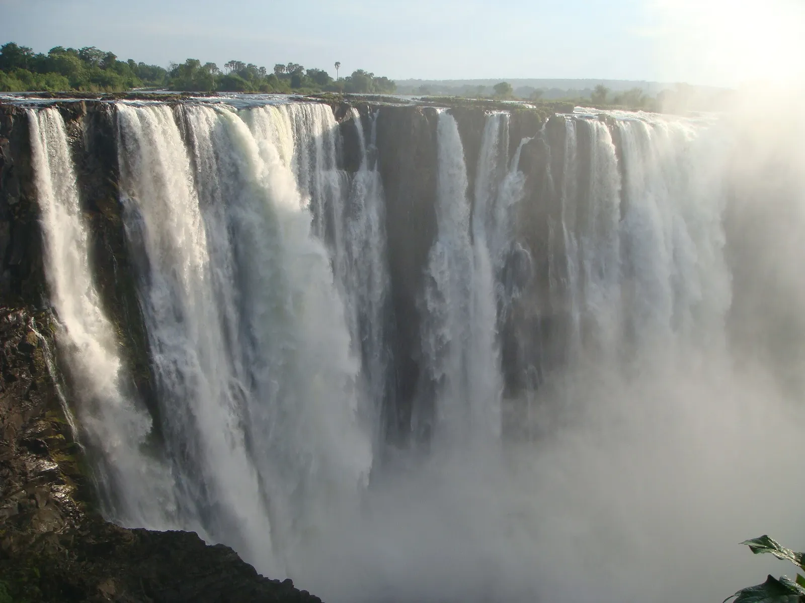 Wide curtain of water pouring over the basalt lip into a misty gorge
