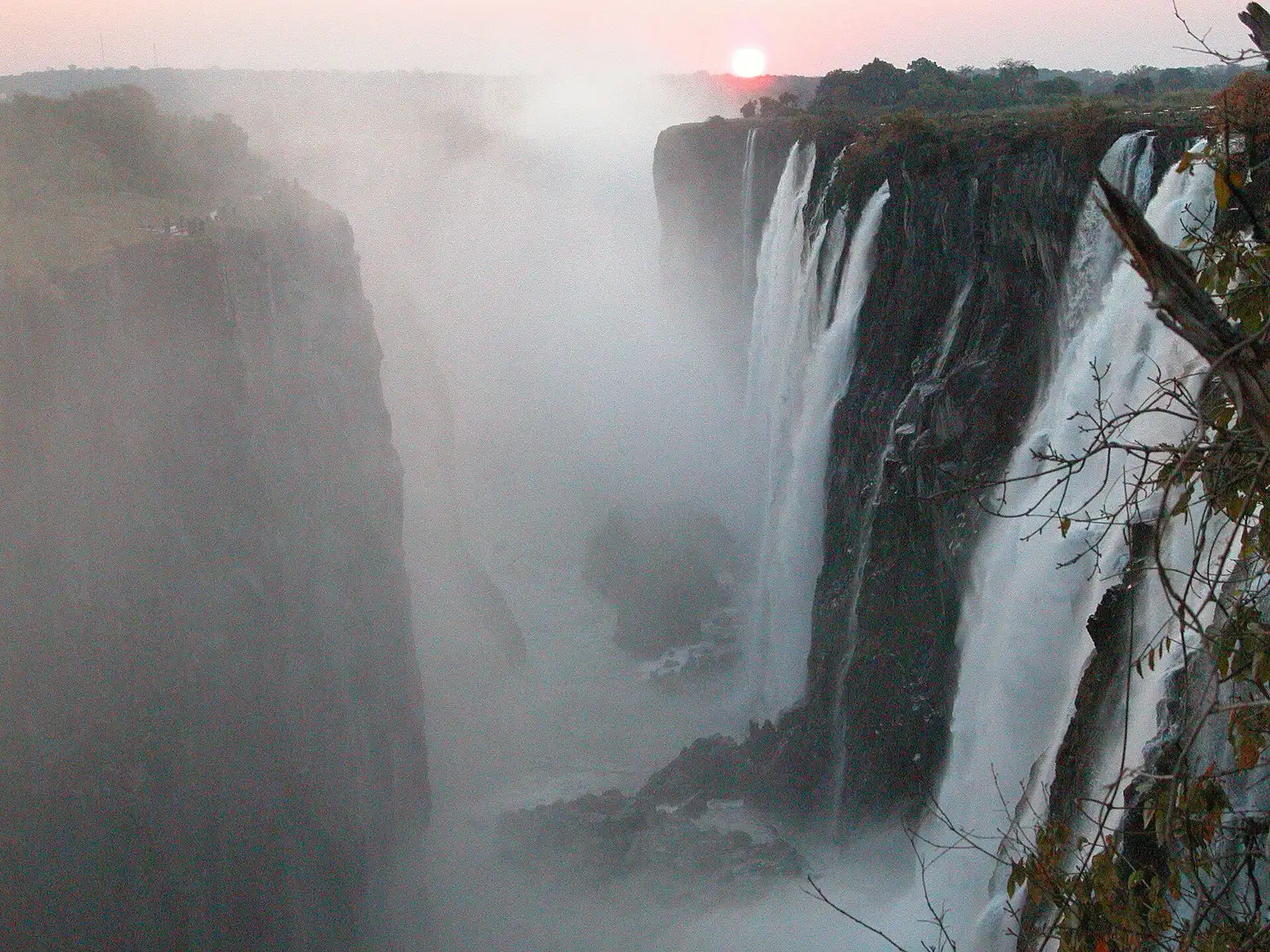 Sun setting over the gorge as spray rises from the falls on the Zambian side
