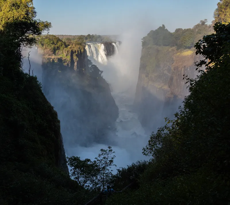 Spray rising from the falls at the end of a deep, tree-lined gorge