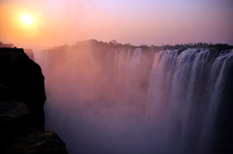 Sun setting behind pink spray over the falls