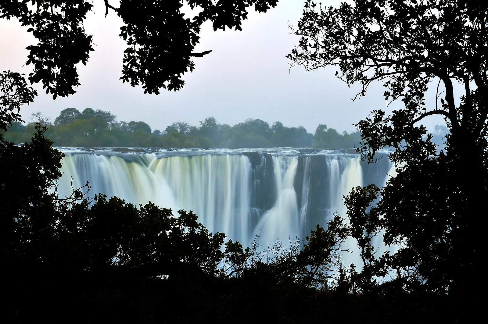The falls framed by dark tree silhouettes