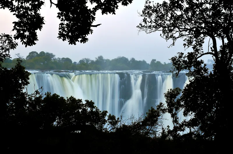 The falls framed by dark tree silhouettes
